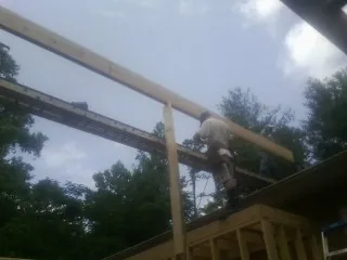 Carpenter setting a ridge beam over a new addition frame — Ice Dam Removal by Roofing Brothers in West New York