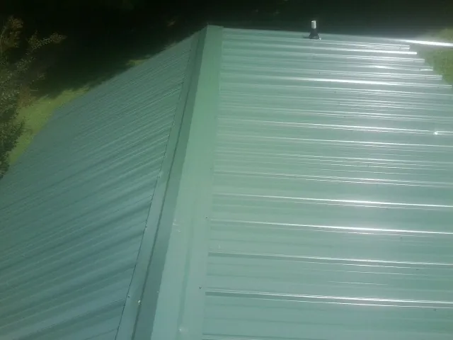 New green metal panels meeting at the ridge of a roof — Flat Roof Repair work by our crew in West New York