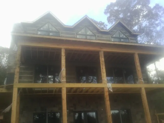 Dormers and porch framing on a large log home under construction — Roof Coating work by our crew in West New York