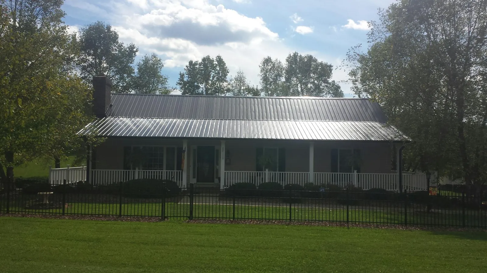 Gray metal roof on a brick ranch with a full width front porch — Gutter Guard Installation work by our crew in West New York