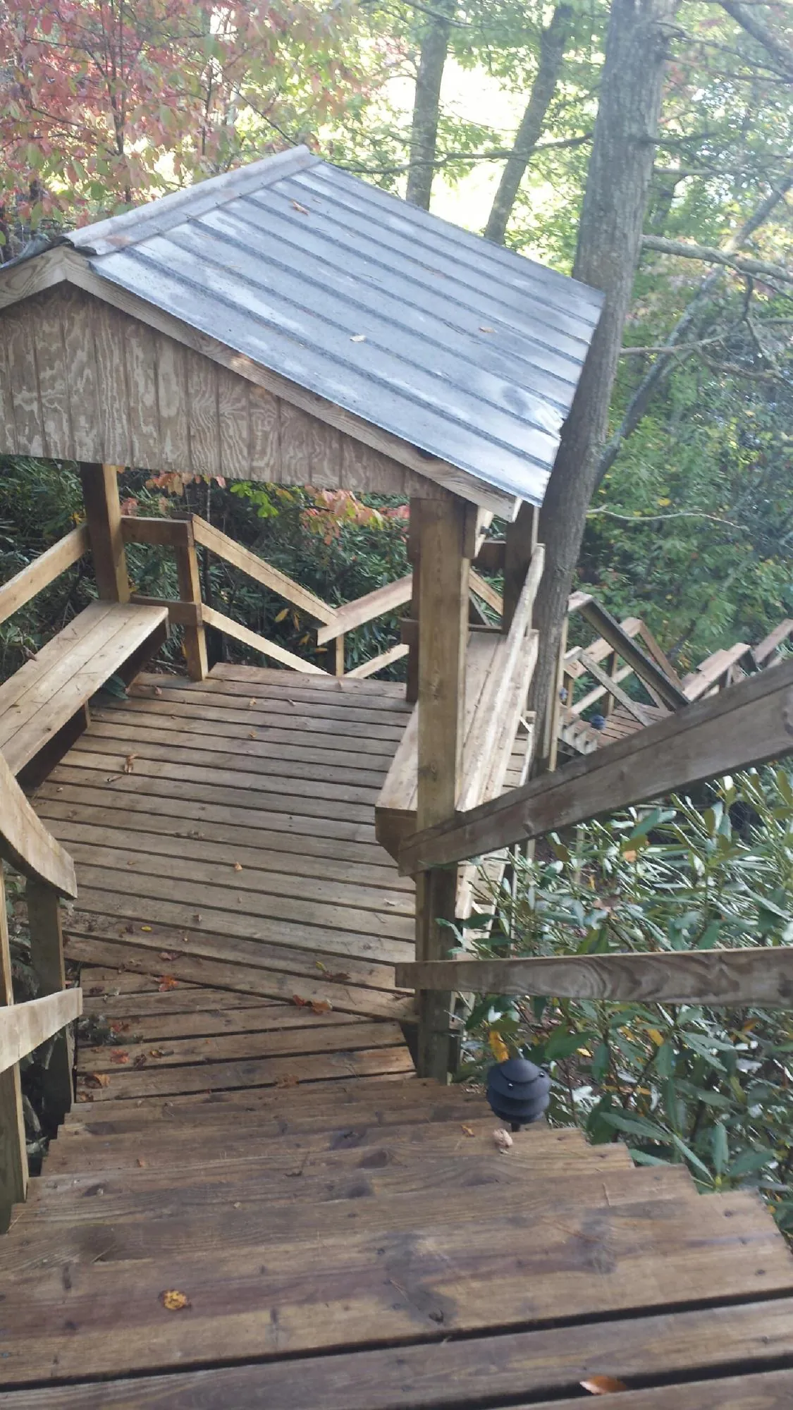 Metal roofed shelter over wooden steps on a wooded walkway — Skylight Repair & Installation work by our crew in West New York