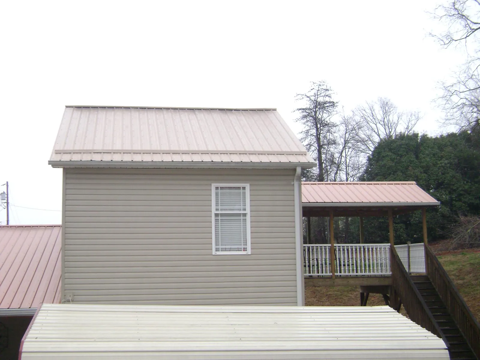 Tan metal roofs on a two story addition and attached porch, from a Roof Replacement job in West New York