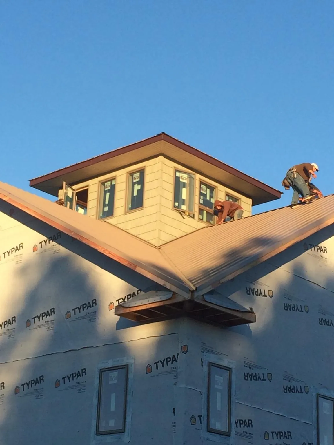 Roofers working around a rooftop cupola on a new metal roof at sunset — Roof Waterproofing in West New York by Roofing Brothers
